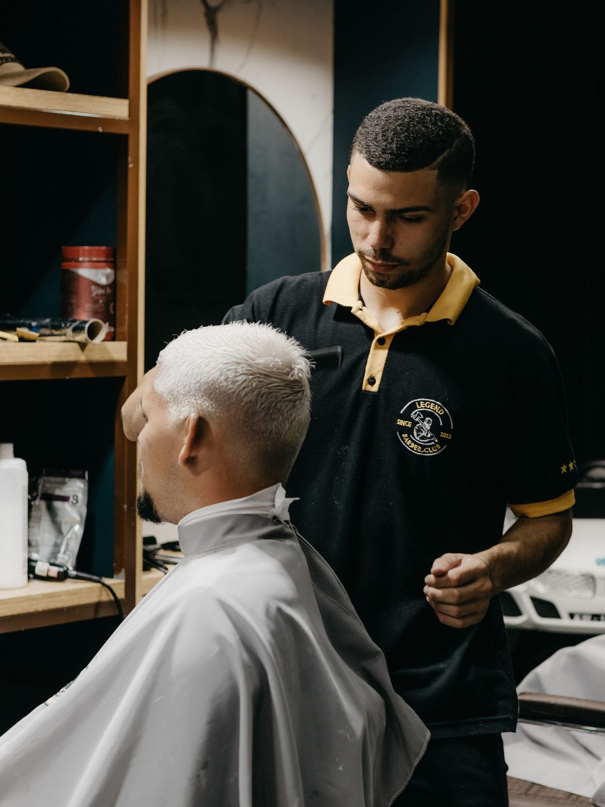 Barber schneidet einem Kunden im weißen Umhang die Haare